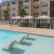 a pool with lounge chairs and umbrellas by a building